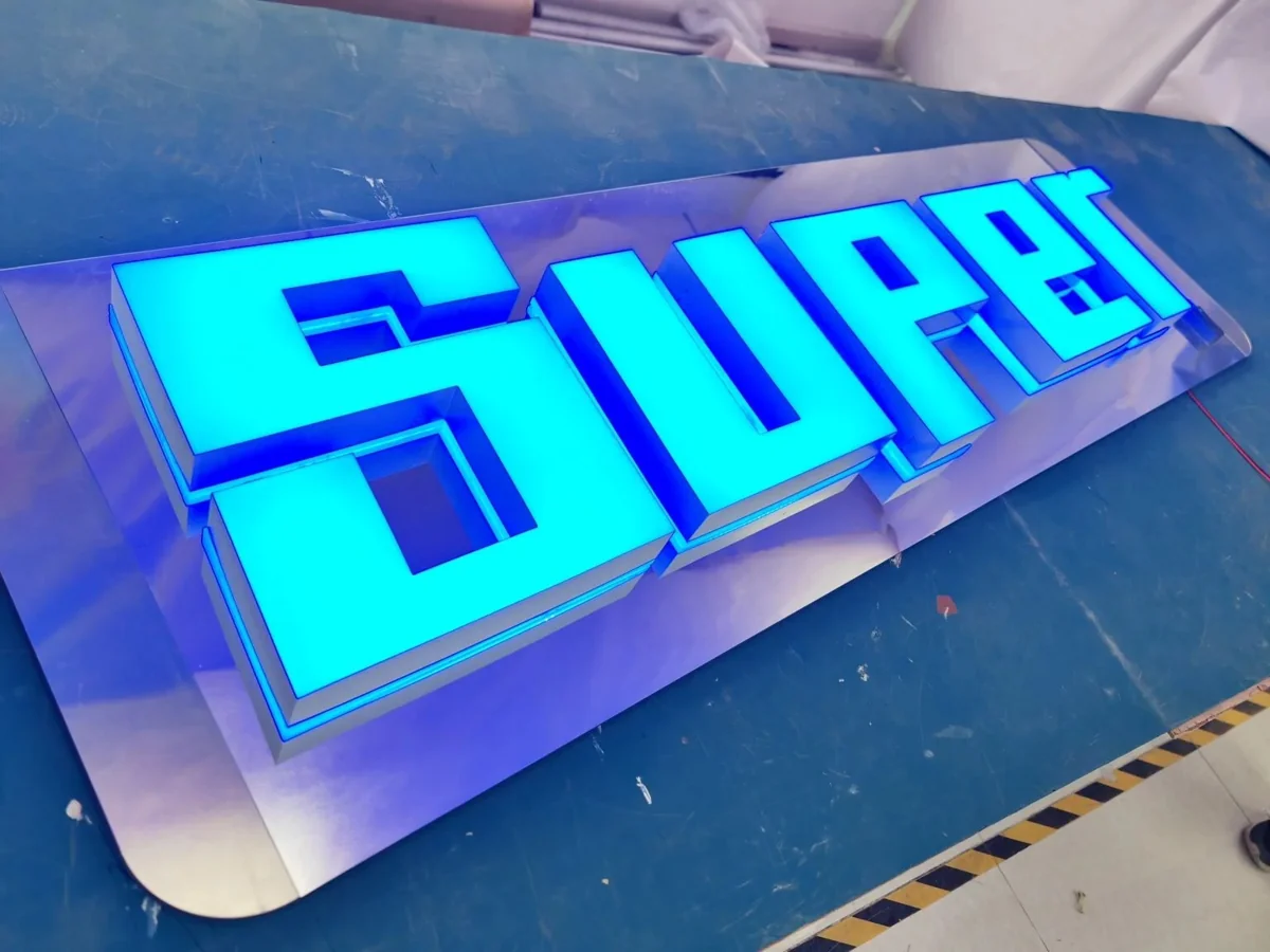 Blue illuminated SUPER channel letters on a work surface